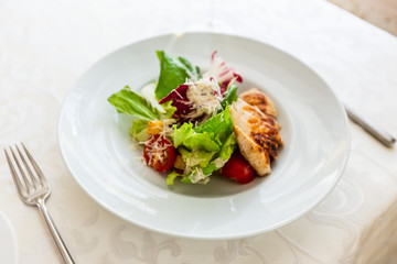 Classic caesar salad with grilled chicken on a white plate