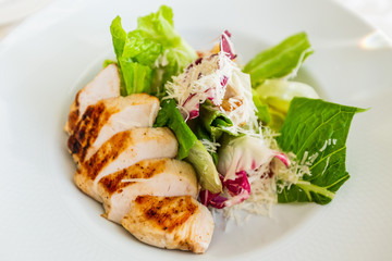Classic caesar salad with grilled chicken on a white plate