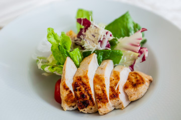 Classic caesar salad with grilled chicken on a white plate