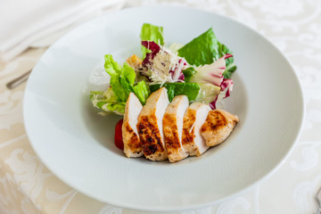 Classic caesar salad with grilled chicken on a white plate