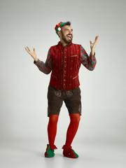 friendly man dressed like a funny gnome posing on an isolated gray background