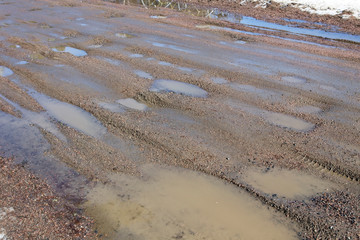 wet dirt road with puddles in spring, Finland