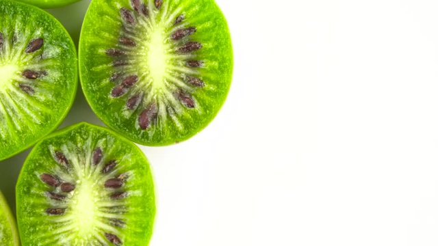 Top view of half frame circle shaped mini kiwi halves. Rotating on the turntable. Isolated on the white background. Close-up. Macro.