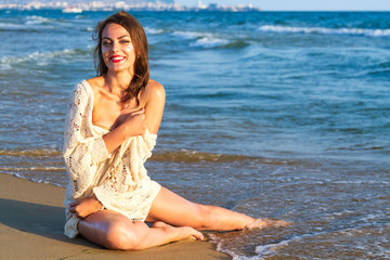 Fototapeta na wymiar Pretty woman in white dress posing on a sea beach