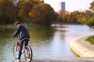 boy ride bicycle on city park lake background fall landscapce