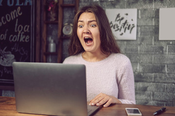 girl looks at laptop with horror, girl terrified