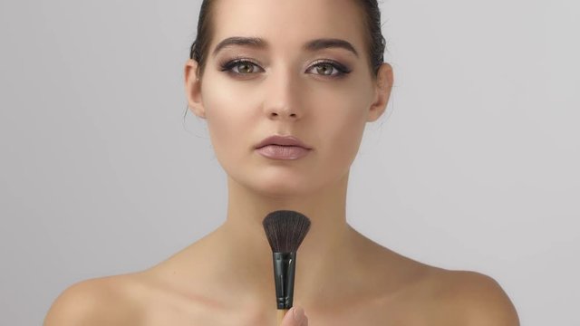 Make up brush, and beauty woman face, . Portrait of attractive young mixed race asian caucasian girl brunette holding symmetrically make-up brush, close up , isolated on white studio shot, Head and