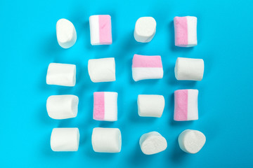 marshmallow laid out on blue paper background. pastel creative textured pattern.