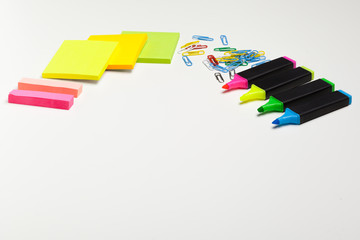 Sticky notes with markers, colored pens, paper clips laying on a table