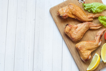 Smoked chicken wings with fresh lettuce tomato and lemon. Copy space
