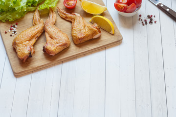 Smoked chicken wings with fresh lettuce tomato and lemon. Copy space