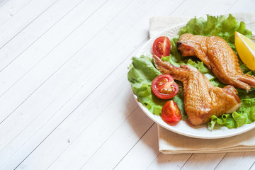 Smoked chicken wings with fresh lettuce tomato and lemon. Copy space