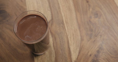 Hot cocoa in glass on wood background with copy space