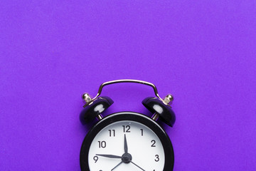 black vintage alarm clock on color background