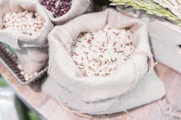 Grains, beans, grains and rice in a calico bag on a wooden table.