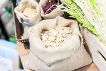 Grains, beans, grains and rice in a calico bag on a wooden table.