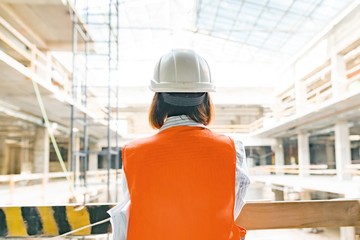 Female engineer on construction site, view from the back. Building, development, teamwork and...