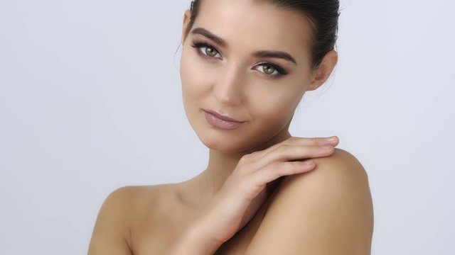 Beautiful Young Woman with Clean Fresh Skin louching her face and body look away .Girl beauty face care. Facial treatment . Cosmetology , beauty and spa .Slow motion 4K UHDhigh quality sharp footage.