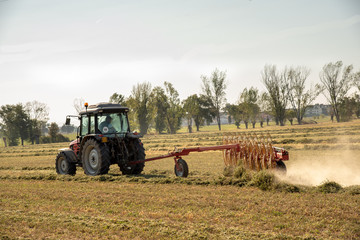 Obraz premium Trattore al lavoro in campo di fieno