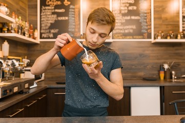 Portrait of young male barista making drinks. Coffee shop business concept