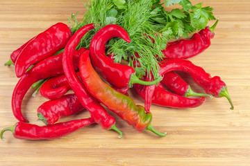 Red chili and greens on bamboo wooden surface close-up