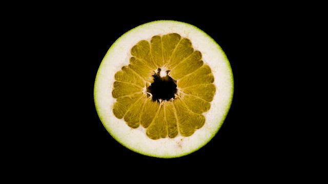 Top view from above of big shaddock pomelo fruit cross section cut. Slowly rotating on the turntable. Isolated on the black background. Close-up. Macro.