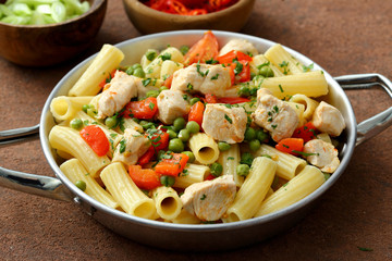 Pasta maccheroni con pollo piselli e verdure in padella di metallo 