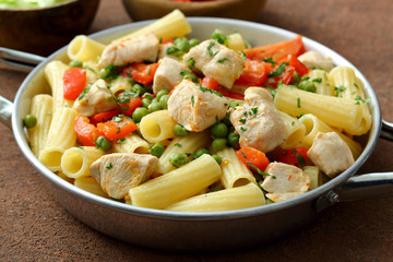 Pasta maccheroni con pollo piselli e verdure in padella di metallo 