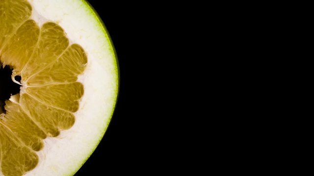 Top view from above of half cut shaddock pomelo fruit. Slowly rotating on the turntable. Isolated on the black background. Close-up. Macro.