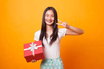 Young Asian woman show Victory sign with a gift box.