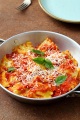 Pasta Italiana ravioli ripieni con salsa di pomodoro e parmigiano su tavolo di cucina,