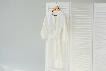 elegant white dress hanging on wooden room divider