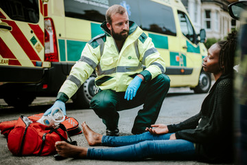 Male paramedic checking on an injured woman on a road © Rawpixel.com