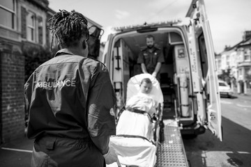 Paramedics moving a young patient on a stretcher into an ambulance