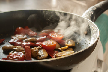 Mushrooms & Tomatos sizzling in a frying pan