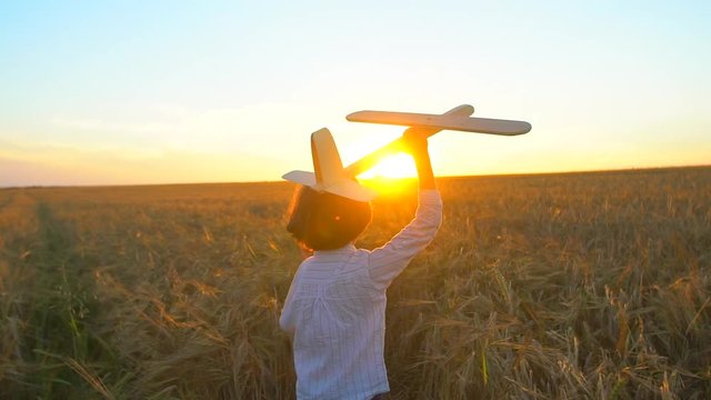 Happy little boy child running with toy airplane in wheat field at sunset. Kid playing with airplane in summer nature outdoors. Little pilot dreaming of flight travel vacation happy family big dream.