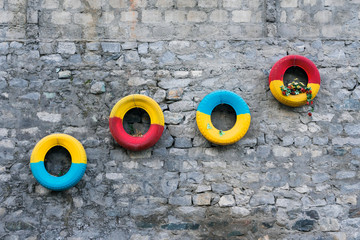 Colorful tires decorated on a stony wall - Powered by Adobe
