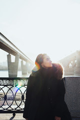 Lifestyle portrait of young adult female in warm winter clothing standing in the light, selective focus