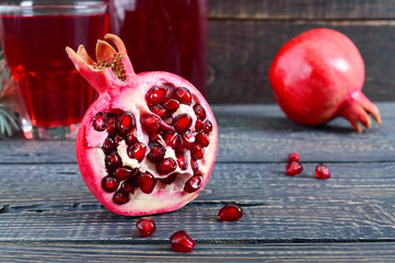 A glass of fresh pomegranate juice with ripe pomegranate fruits on wooden table. Vitamins and...
