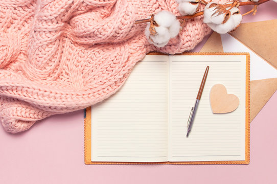 Female pink knitted sweater, cotton, open blank notebook, love letter on pastel pink background top view flat lay. Lady winter Clothes. Cotton flowers. Lifestyle gentle female background