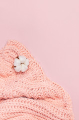 Female pink knitted sweater pullover and flower of cotton on pastel pink background top view flat lay. Fashion Lady Clothes Jumper Autumn winter clothes fashion look Delicate cotton flowers Lifestyle