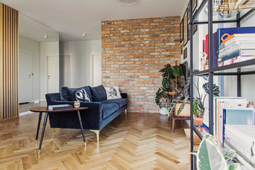 Stylish scandinavian open space with dining and living room with design sofa nad bookstand. Bright...