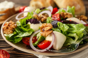 Delicious fresh salad with walnuts on plate, closeup