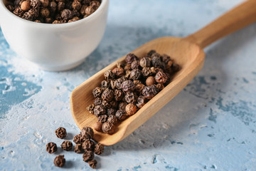 Wooden scoop with peppercorn on table