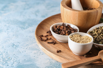 Wooden plate with spices on table