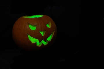 halloween pumpkin with green eyes on black background