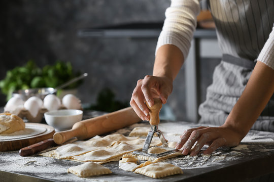 Woman making tasty ravioli on table