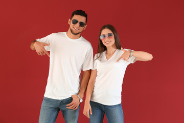 Young man and woman in stylish t-shirts on color background
