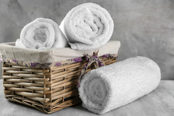 Fototapeta na wymiar Wicker basket with soft towels on grey table