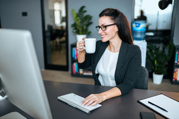 Portrait of a successful business woman drinking tea at work in modern office.